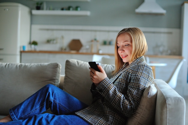 Photo woman use of smartphone in the evening at home while laying on sofa