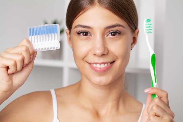 The woman uses brushes to clean the interdental spaces