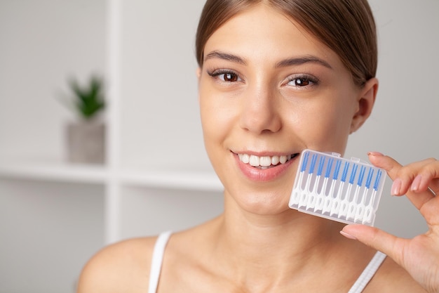 The woman uses brushes to clean the interdental spaces