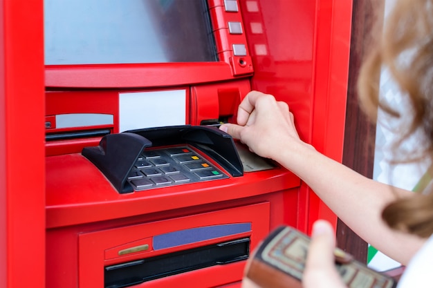 Woman uses a credit card at ATM close up