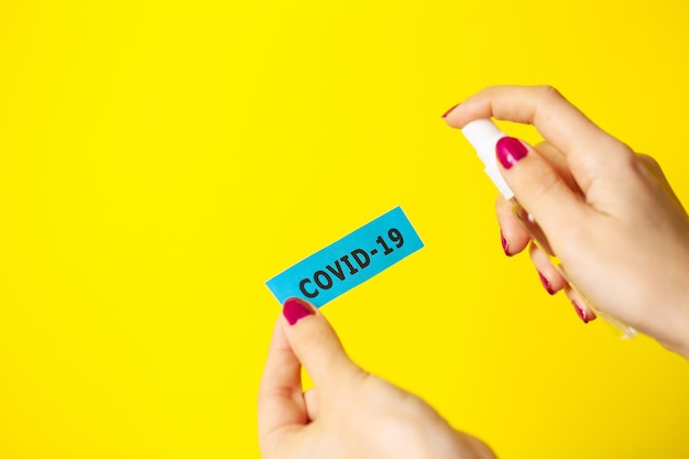 Woman uses hand antiseptic on yellow background