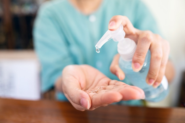 Woman uses a hand washing gel to wash her hands to avoid contamination. Clear sanitizer in pump bottle, for killing germs, bacteria and virus.