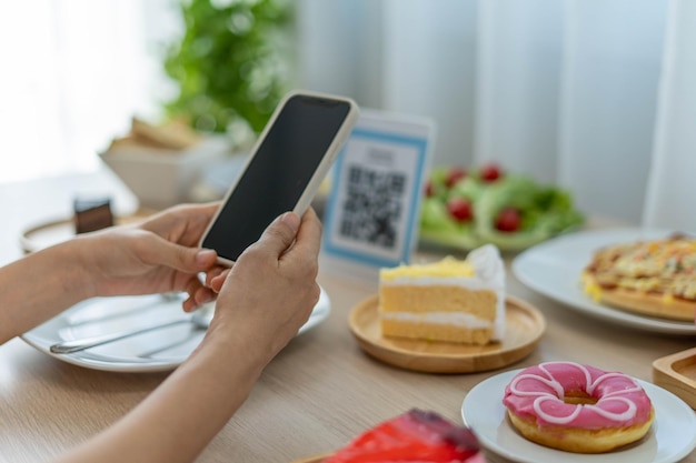 A woman uses her phone to scan a QR Code to receive a discount or pay for food The idea of using your phone to transfer money or pay online without cash