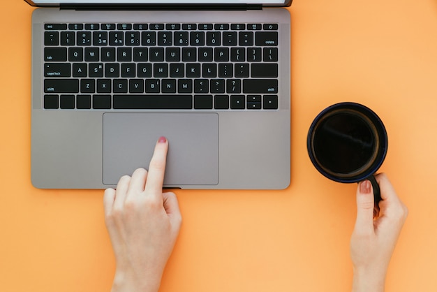 Woman uses a laptop on an orange surface