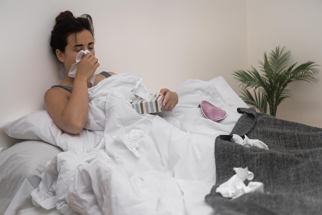 女性は鼻水のためにナプキンを使い ⁇ 病気から回復するために医療用ドロップを握っています ⁇