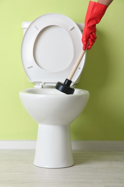 Woman uses a plunger to unclog a toilet bowl in a bathroom