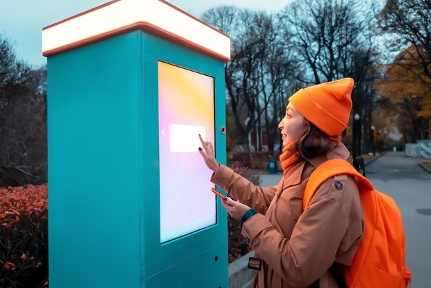 A woman uses a selfservice kiosk to print photos from her smartphone on a city street