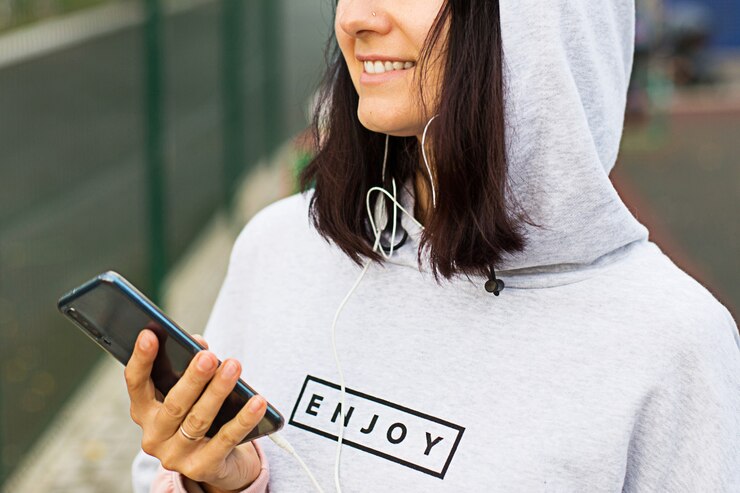 Photo 女性はスマートフォンを使って音楽を聴く