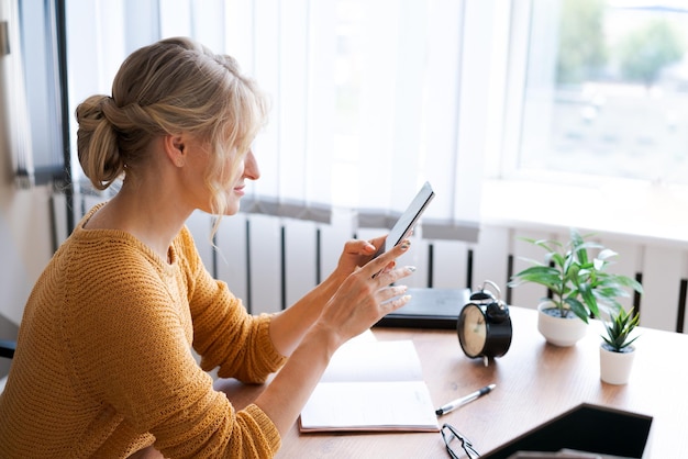 女性はオフィスでスマートフォンを使用しています美しい女の子が携帯電話を見ています