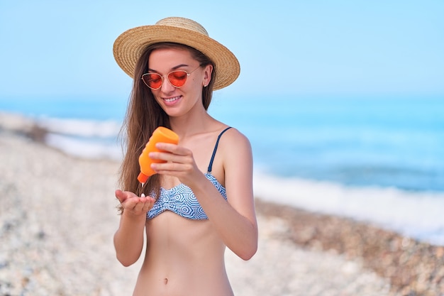 Photo woman uses sunscreen cream during tanning on the sea