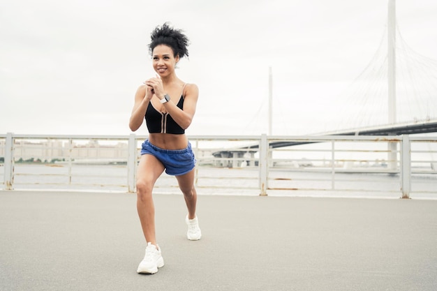 女性は快適なスポーツウェアでスポーツ フィットネスの時計を使用します。