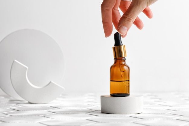 Woman using aromatic lotion oil Hyaluronic acid or collagen in brown bottle with pipette Mock up