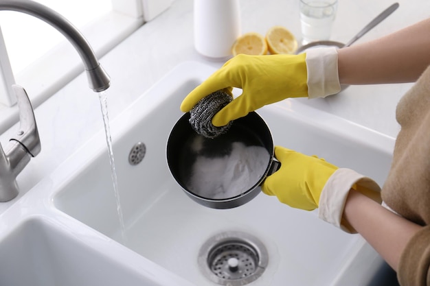 Woman using baking soda and metal sponge to clean pot closeup