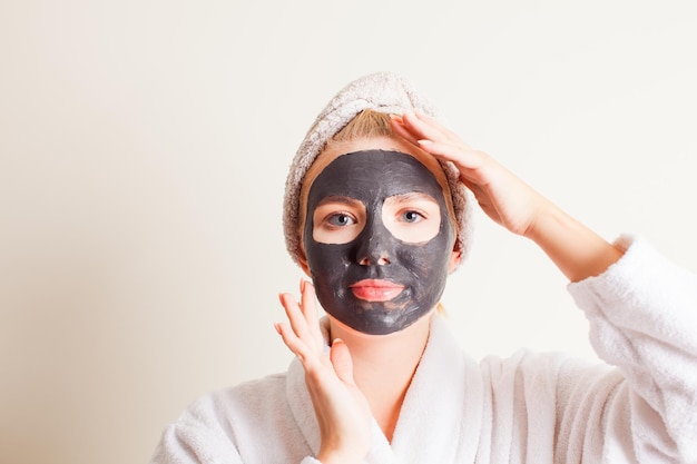 Woman using a black face mask close up face with hands Spa treatment