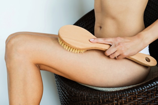 Foto donna che usando la spazzola per massaggiare il corpo a casa