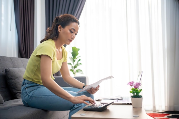 Photo woman using calculator to check total sum of household bills