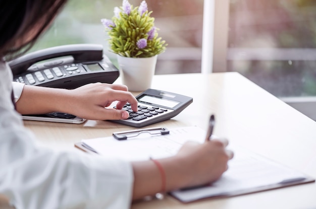 Woman using calculator and make a note