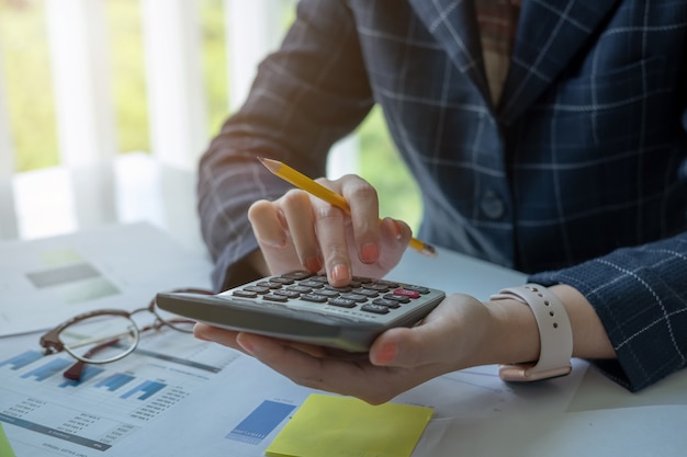 Donna che per mezzo del calcolatore mentre lavorando per i documenti finanziari