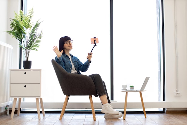 Женщина с помощью мобильного телефона на палке в интерьере офиса