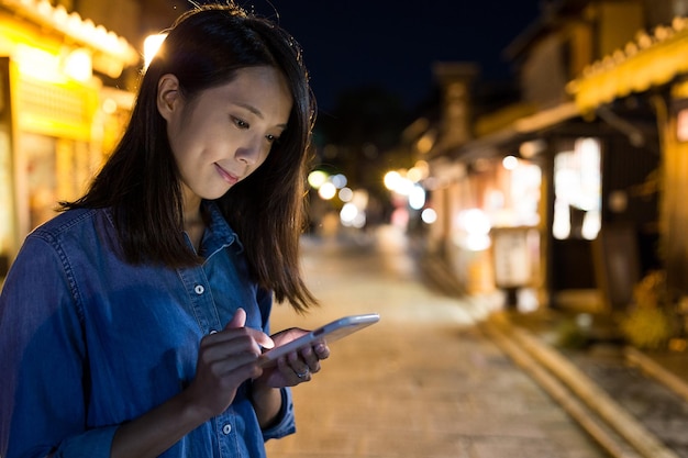 Woman using cellphone at night in Kyoto city