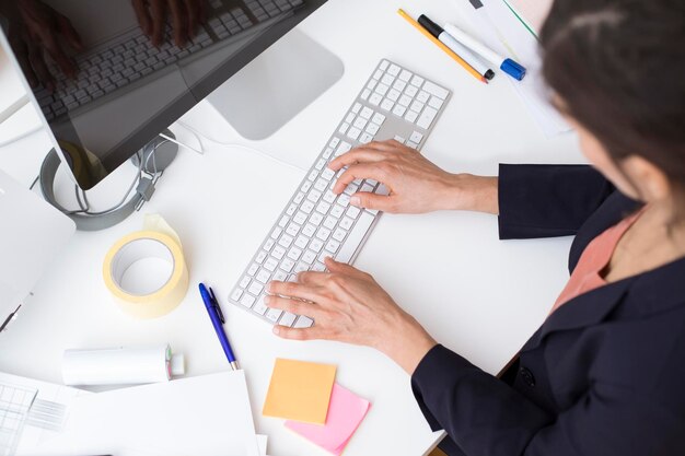 Woman using computer keyboard at desk in office