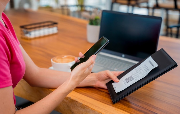 Photo woman using contactless payment by mobile phone with qr code at cafe