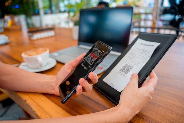 Woman using contactless payment by mobile phone with qr code at cafe