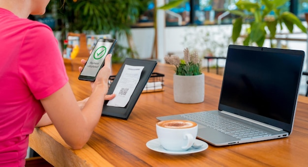 Woman using contactless payment by mobile phone with qr code at cafe