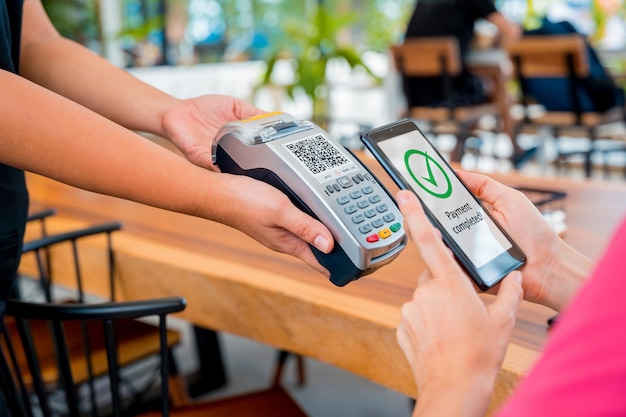 Женщина использует бесконтактную оплату мобильным телефоном с qr-кодом в кафе