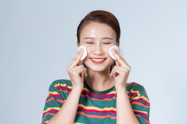 Woman using cotton pad Happy smiling beautiful young woman cleaning skin by cotton pad