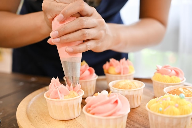 Woman using cream squeeze bag to decorating the cupcake making cupcake