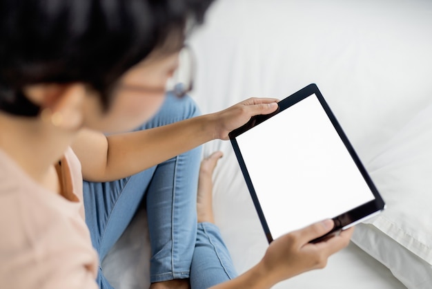 Woman using digital tablet on bed. 