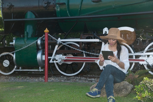 Foto donna che usa un tablet digitale mentre è seduta contro il treno