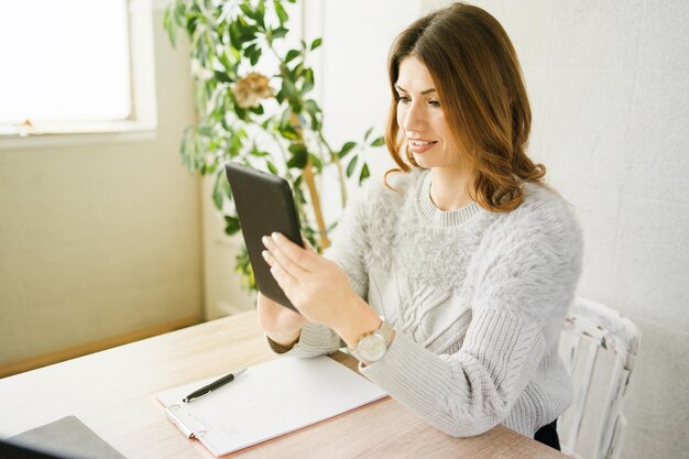 Женщина использует цифровой планшет, сидя дома