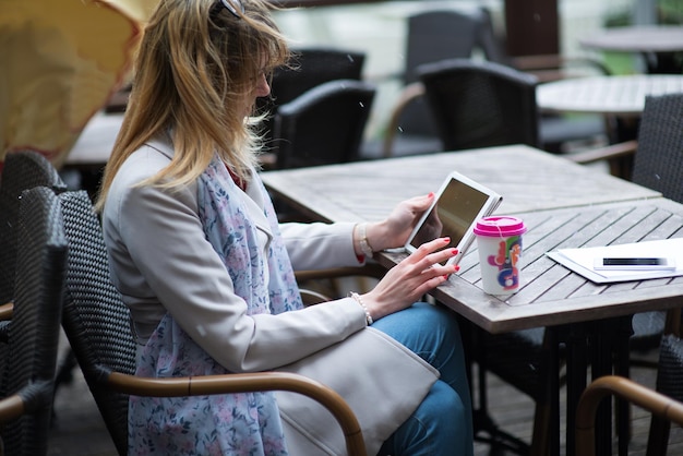 Photo woman using digital tablet while sitting at table