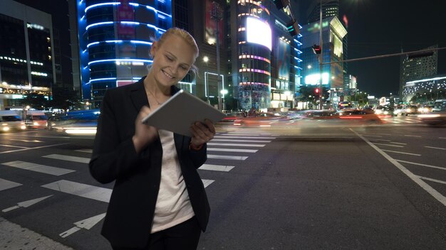 Foto donna che usa un tablet digitale mentre è in piedi sulla strada in città