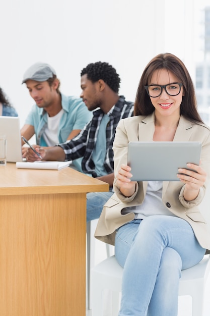 Woman using digital tablet with colleagues behind in office