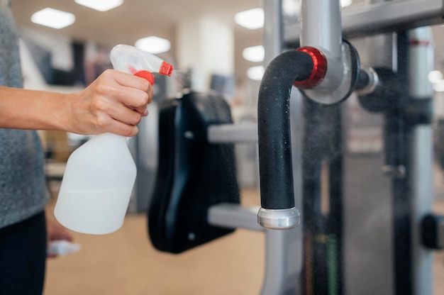 Photo woman using disinfectant on gym equipment