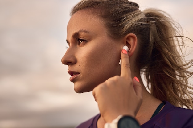 Donna che usa gli auricolari durante l'allenamento all'aperto