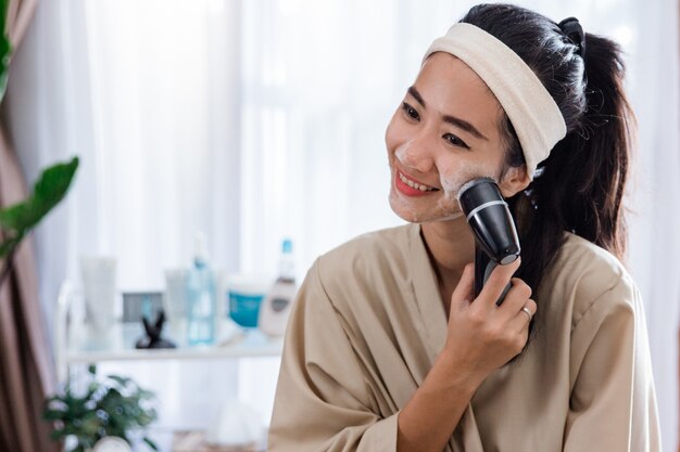 Woman using electric facial cleanser machine