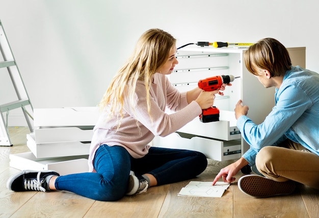 Woman using electronic drill install cabinet