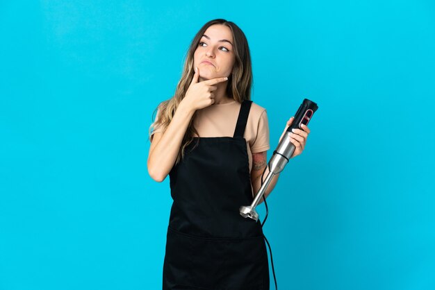 woman using hand blender posing isolated against the blank wall