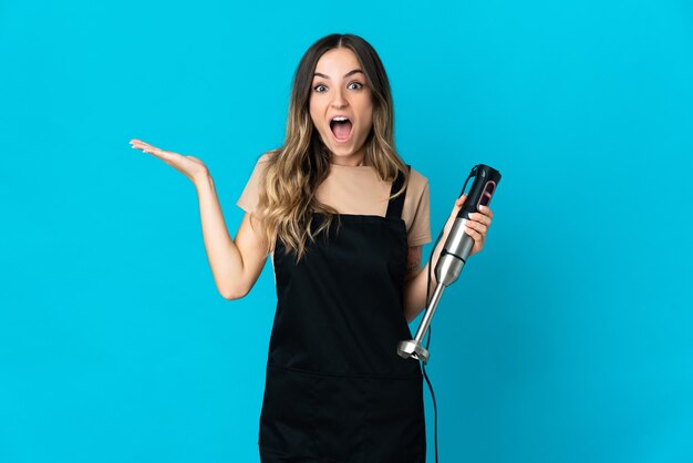 woman using hand blender posing isolated against the blank wall