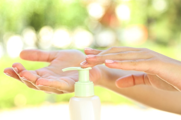 Woman using hand cream outdoors on blurred background