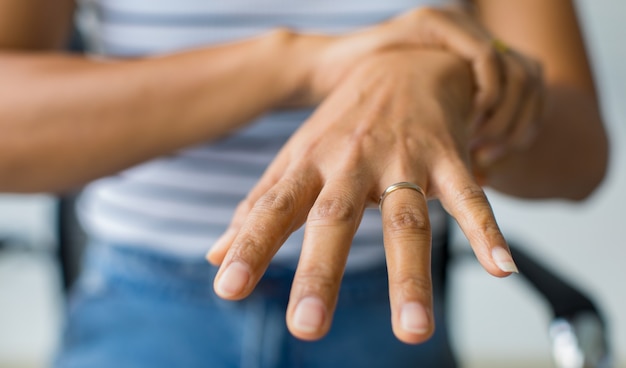 Foto donna che usa la mano per tenere il polso e allungare le dita con dolore, sofferenza, dolore e formicolio. concetto di sindrome di guillain barre e malattia delle mani insensibili.