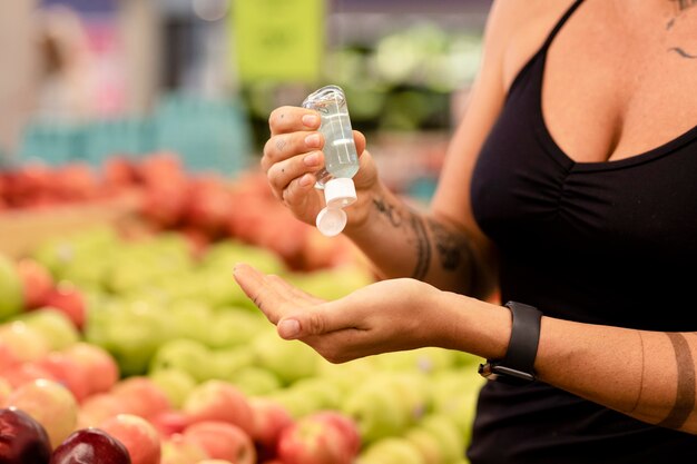 手指消毒剤を使用している女性、食料品の買い物画像