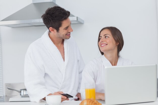 Woman using her laptop while having breakfast