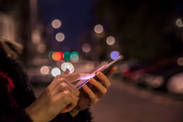 Foto donna utilizzando il suo telefono cellulare, skyline della città di notte luce sfondo