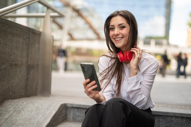 Donna che usa il suo telefono cellulare per ascoltare musica mentre si siede sulle scale all'aperto