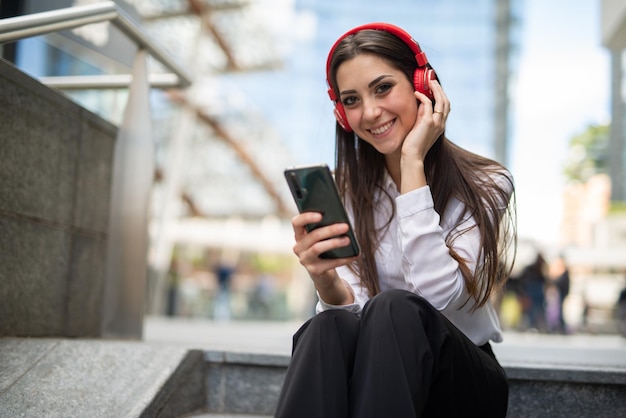 Donna che usa il suo telefono cellulare mentre si siede sulle scale all'aperto